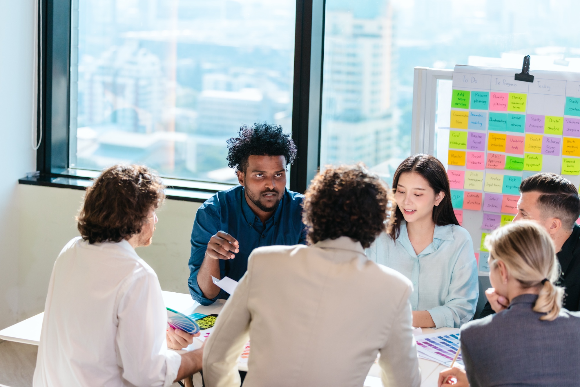 Workshop-Teilnehmende diskutieren gemeinsam an einem Tisch vor einem Board mit Notizzetteln